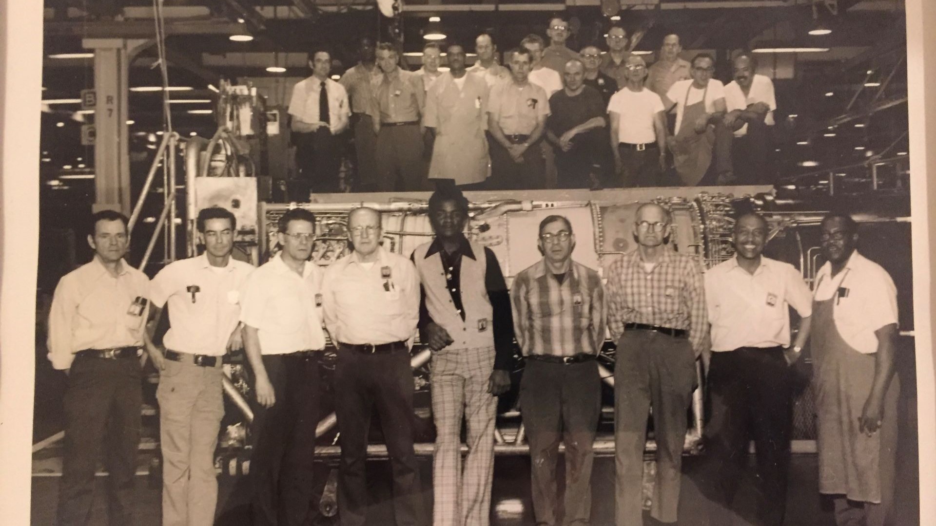 Sepia-tinted photo of a group of men in front of a J79 engine