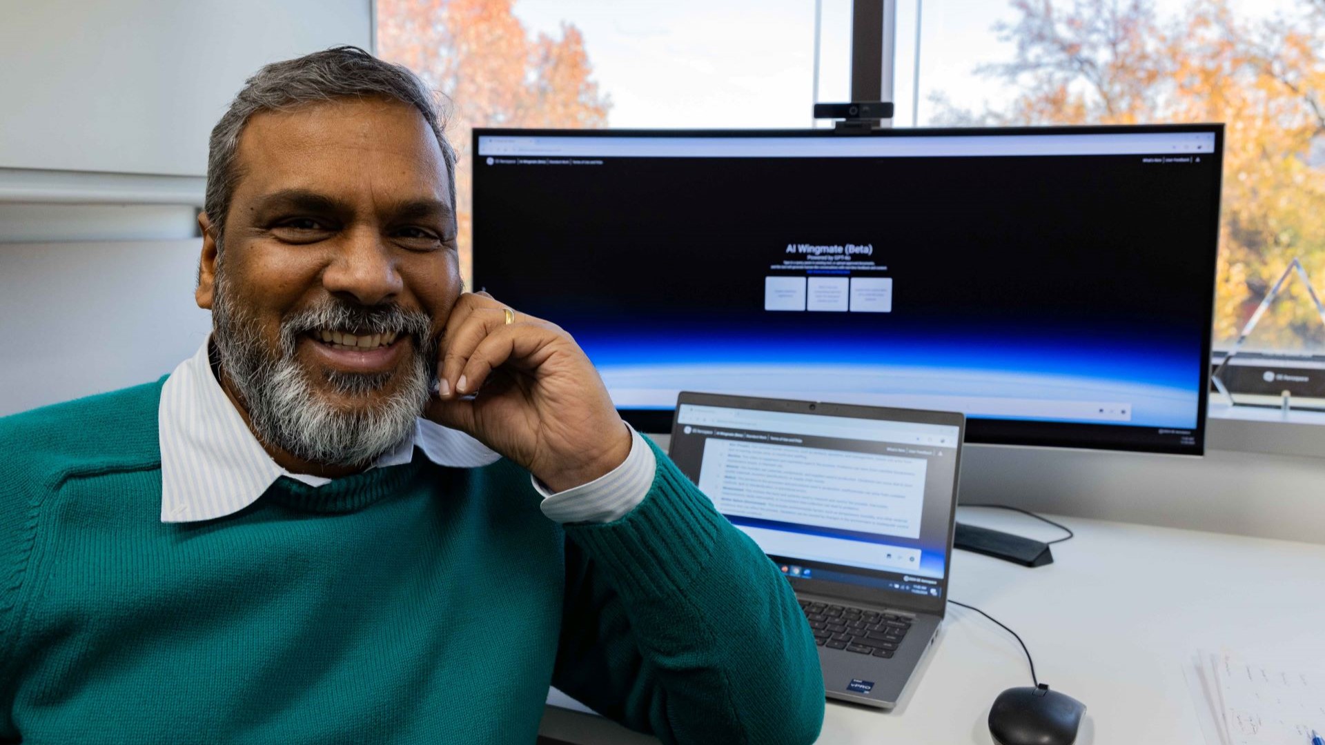 Deshmukh sitting at a desk in front of a large monitor and laptop