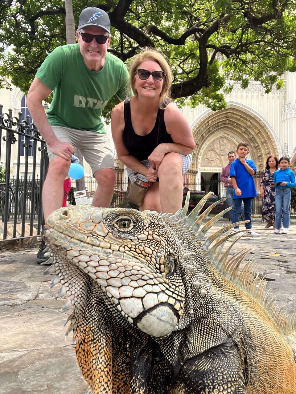 Roberson and his wife posing outdoors for a picture with an iguana in the foreground