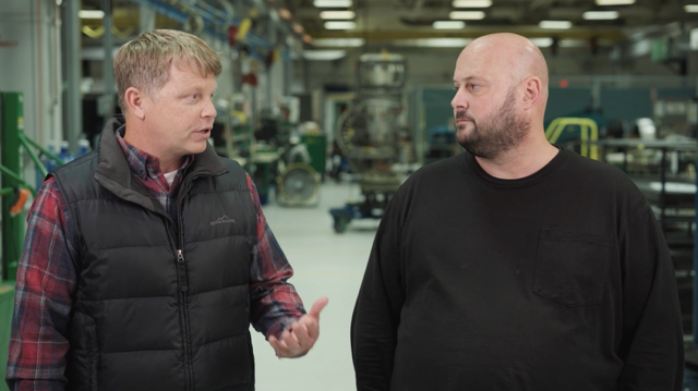 Two men standing on a shop floor talking